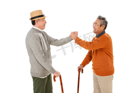 老年人摄影照片_拿着拐杖的老哥俩握手聊天