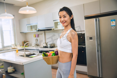 清新运动减肥健身摄影照片_穿着运动装的青年女人在厨房