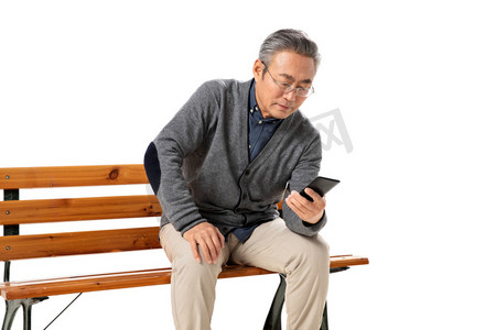 社区展板摄影照片_坐在长椅上的老人看手机