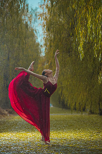 芭蕾女人摄影照片_穿红色裙子的青年女人在户外跳芭蕾舞