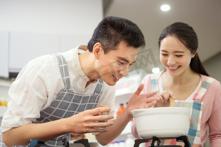 女人煲汤摄影照片_年轻夫妇在厨房煲汤