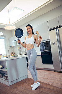 健身用具摄影照片_青年女人在厨房