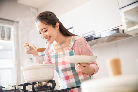 女人煲汤摄影照片_青年女人在厨房煲汤