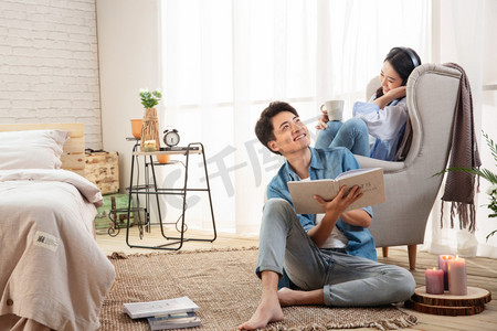 年轻亚洲家庭摄影照片_年轻夫妻在卧室共享休闲时光