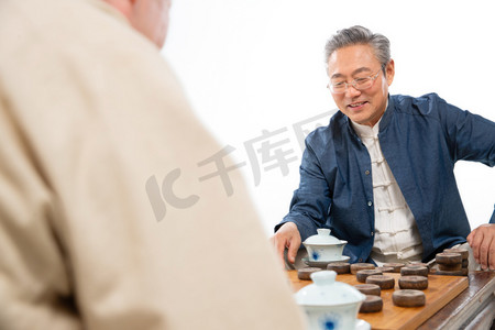 白色桌子桌子摄影照片_两位老年朋友下象棋
