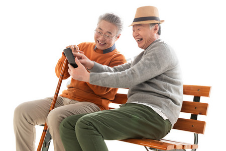 两人聊天摄影照片_两位老年朋友坐在长椅上看手机