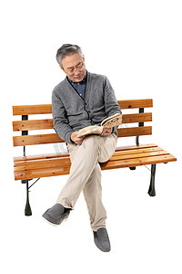 社区老人摄影照片_坐在长椅上的老人看书