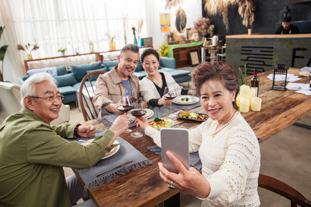 聚餐时中老年人拿手机自拍聚会上快乐的中老年人闲聊叙旧快乐的的中