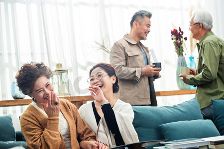 退休的中老年人在居室喝茶聊天看相册