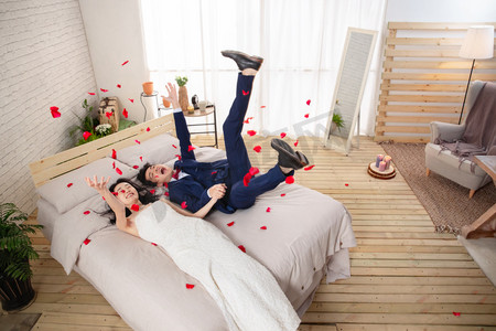 西装皮鞋摄影照片_兴奋的新婚夫妇倒在床上