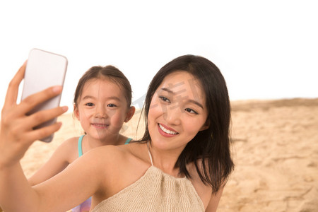母亲和女儿在沙滩上拍照