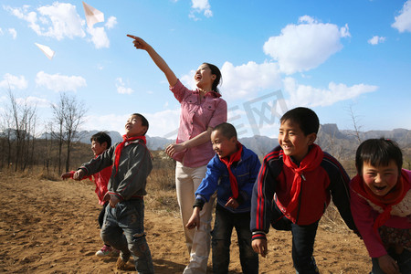 放飞机男孩摄影照片_乡村老师和学生放纸飞机