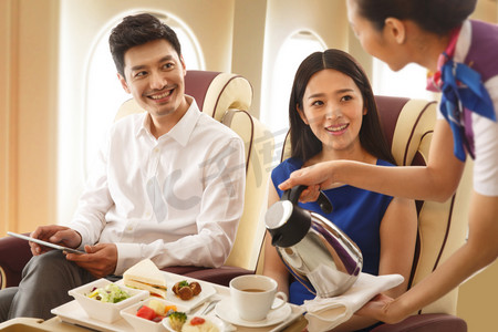 飞机度假摄影照片_年轻夫妇在飞机上用餐