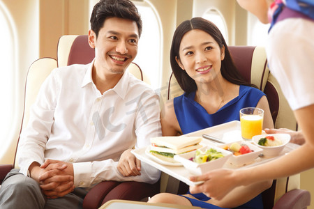 飞机上摄影照片_年轻夫妇在飞机上用餐