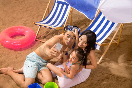 夏季沙滩游泳摄影照片_幸福家庭在沙滩上玩耍