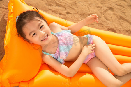 儿童游泳圈摄影照片_可爱的小女孩在沙滩上玩耍
