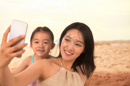 母亲和女儿在沙滩上拍照