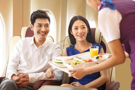 托盘图片摄影照片_年轻夫妇在飞机上用餐