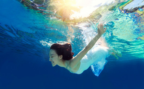 丝质裙子摄影照片_年轻女人在水下游泳