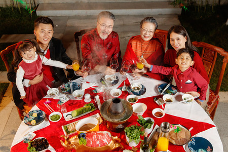 春节传统食物摄影照片_东方家庭在中式庭院内干杯庆祝新年