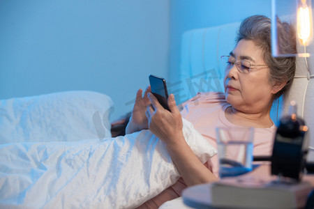 老年人看书摄影照片_老年夫妇坐在床上看手机
