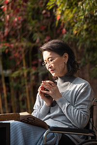 户外老年女人坐在轮椅上看书