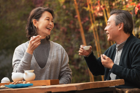快乐的老年夫妇在庭院内品茶