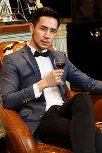 中国红传统摄影照片_青年男人拿着红葡萄酒杯