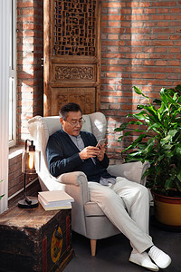 沙雕人物表情摄影照片_休闲的老年男人坐在沙发上玩手机