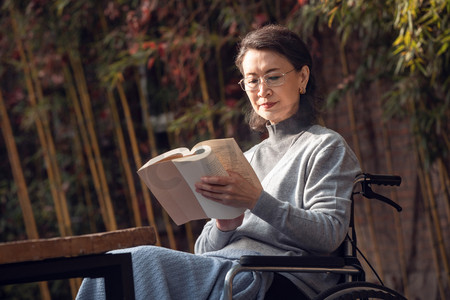 户外读书摄影照片_户外老年女人坐在轮椅上看书