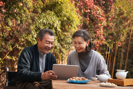 幸福生活摄影照片_老年夫妇在庭院内使用平板电脑