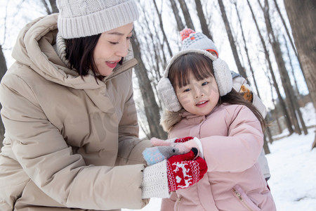 雪树林摄影照片_妈妈给女儿戴手套