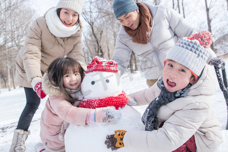 欢乐家庭在雪地里堆雪人