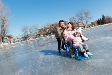 快乐的一家三口坐冰车玩耍