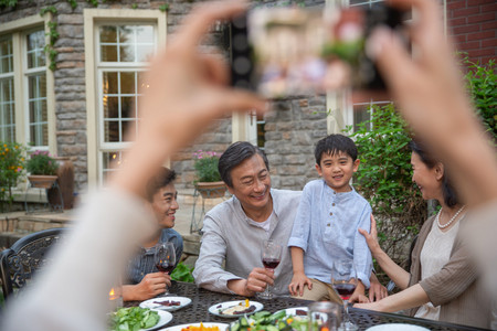 高举酒杯摄影照片_快乐大家庭在庭院里用餐