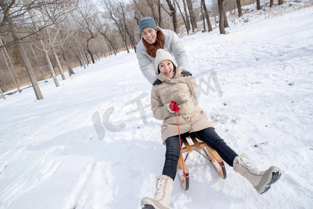 雪树林摄影照片_青年夫妇在雪地上玩雪橇