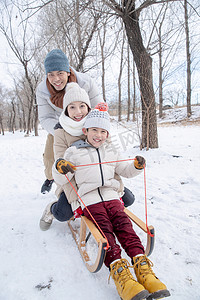 在雪地上玩雪橇的一家人