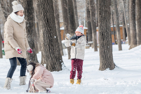 冬天雪景打雪仗摄影照片_雪地里打雪仗的一家人