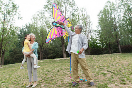 风筝摄影照片_老年夫妇带着孙女在公园里放风筝