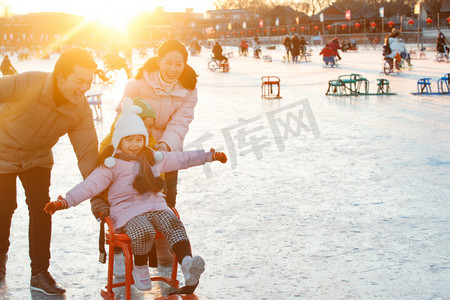 人车冬季摄影照片_一家四口在滑冰场坐冰车玩耍