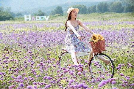 自然美摄影照片_青年女人在花海里骑自行车