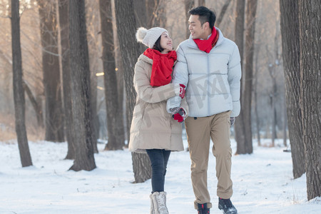 雪树林摄影照片_雪地上散步的青年夫妇