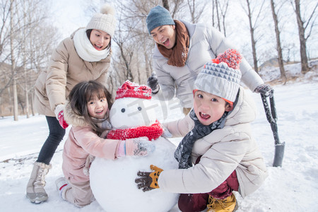 雪地里的雪人摄影照片_欢乐家庭在雪地里堆雪人