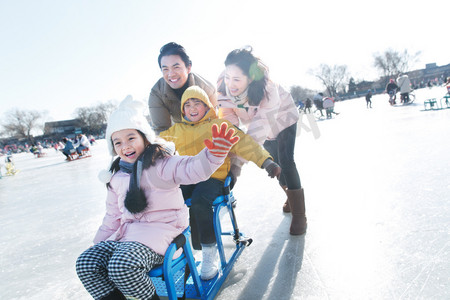 人车冬季摄影照片_快乐的一家四口坐冰车玩耍
