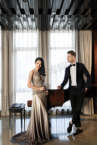 西装晚礼服摄影照片_浪漫的青年男女斜靠着钢琴