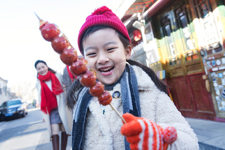 老北京糖葫芦摄影照片_快乐的小女孩吃糖葫芦
