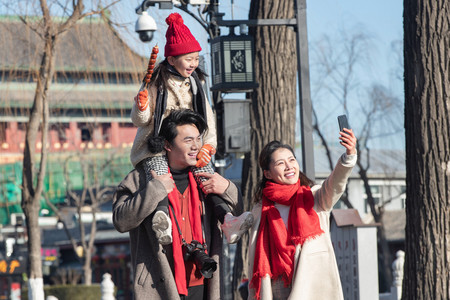老北京糖葫芦摄影照片_年轻父母带着女儿快乐旅行