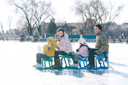 人车冬季摄影照片_快乐的一家四口坐冰车玩耍