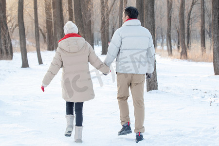 浪漫夫妇手牵手摄影照片_雪地上散步的青年夫妇