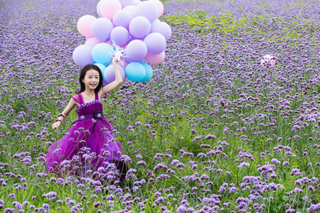 天真摄影照片_拿着气球的小女孩在花海里奔跑